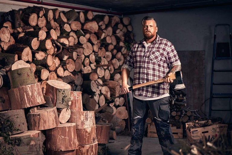 Mann mit Axt vor Holzstapel