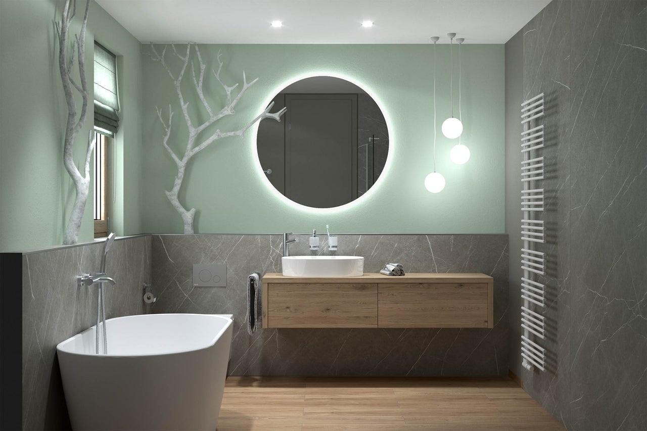 Modernes Badezimmer mit freistehender Badewanne, hölzernem Waschtisch, rundem LED-Spiegel und großformatigen Fliesen in Marmoroptik.