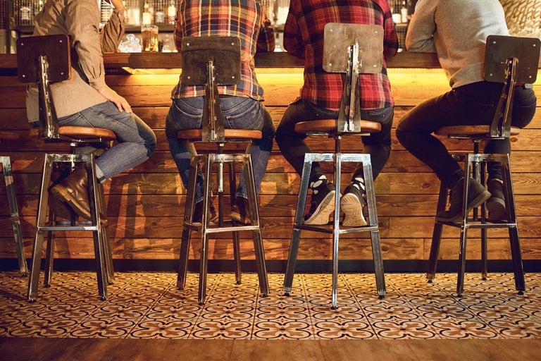Szene mit Personen, die auf Barhockern an einem Tresen sitzen