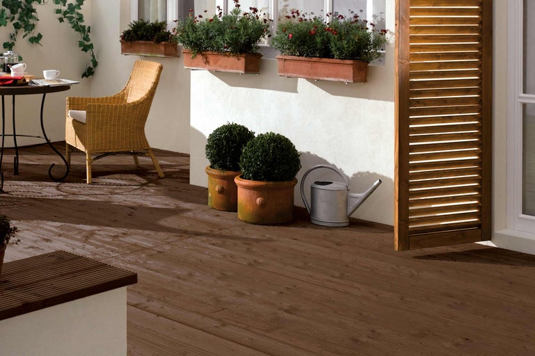 Terrasse mit Holzfliesen, Tisch, Stuhl, Pflanzen und Gießkanne