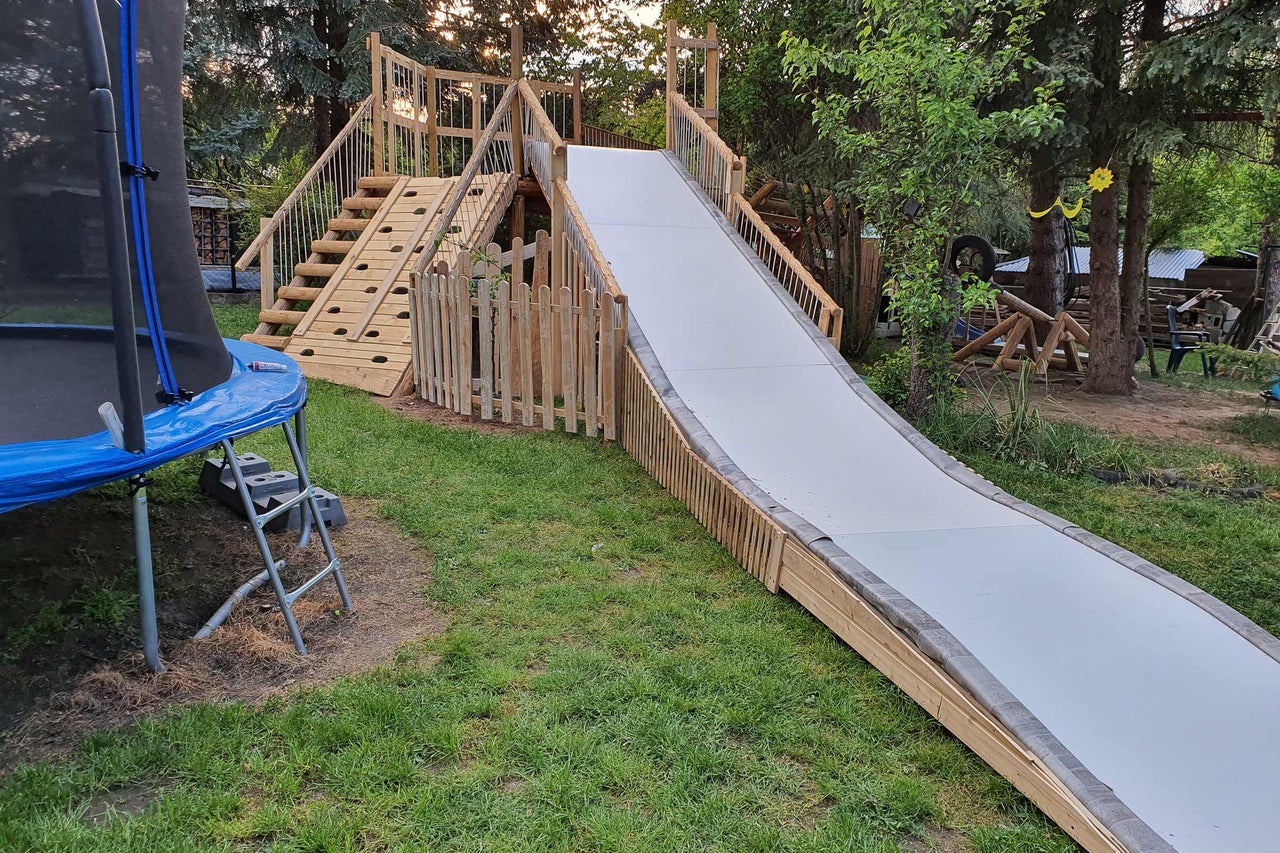 Spielplatz mit Rutsche, Kletterwand und Trampolin im Garten