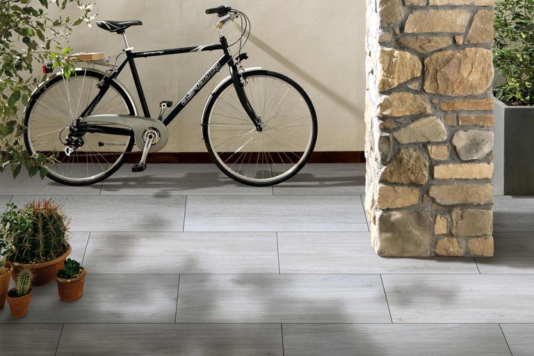 Boden mit grauer Fliesenoptik, Fahrrad und Steinsäule