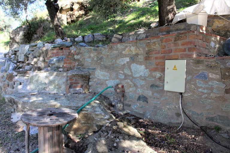 Außenbereich mit Steinmauer, Stromkasten und Holzspule