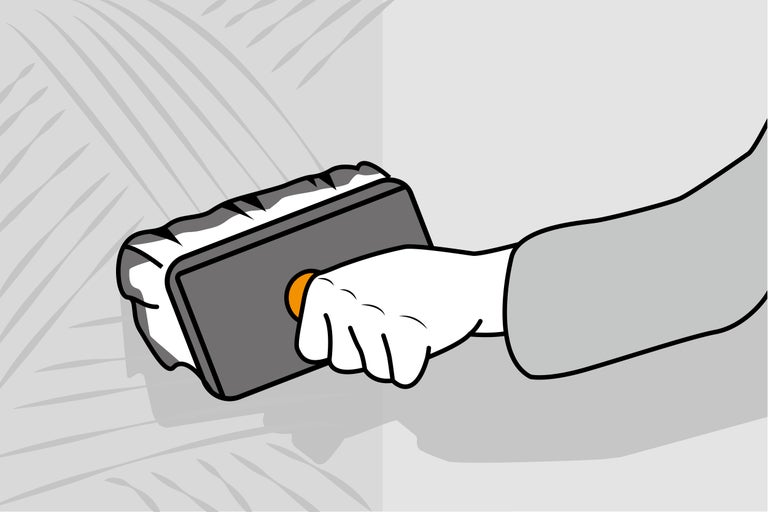 Hand die ein Reibebrett auf eine Wand aufträgt