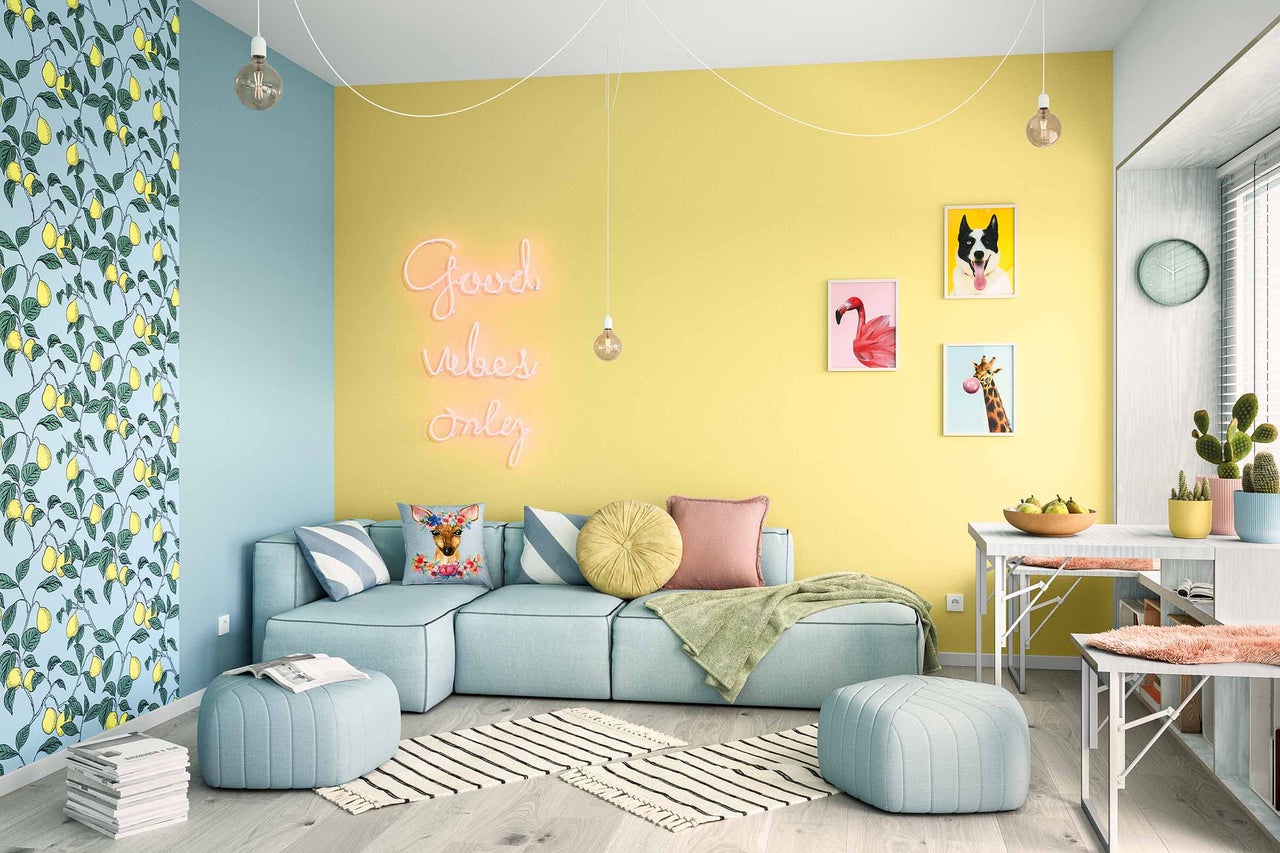 Heller Wohnraum mit Sofa, Kissen, Hockern, Teppich und Wanddekoration