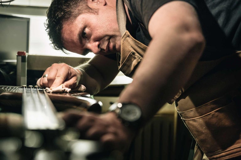 Ein Mann reinigt ein Instrument mit einem Tuch.