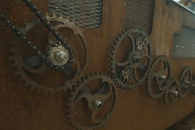 Nahaufnahme von Metallzahnrädern mit Kette auf einer Holzoberfläche