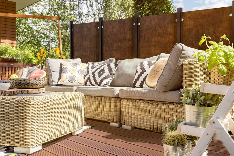 Szene einer Terrasse mit Rattanmöbeln, Kissen und dekorativen Elementen