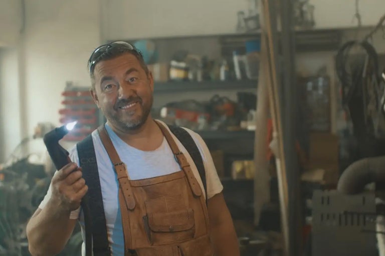 Ein Mann mit Stirnlampe und Lederlatzschürze in einer Werkstatt.