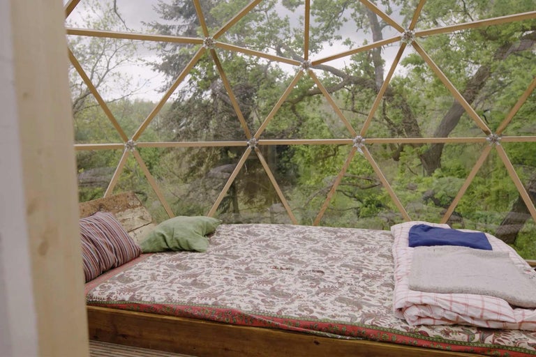 Interieur eines Geodätischen Doms mit Bett und Blick auf die Natur