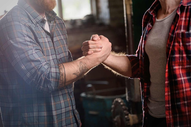 Zwei Handwerker schütteln sich die Hände als Geste der Zusammenarbeit