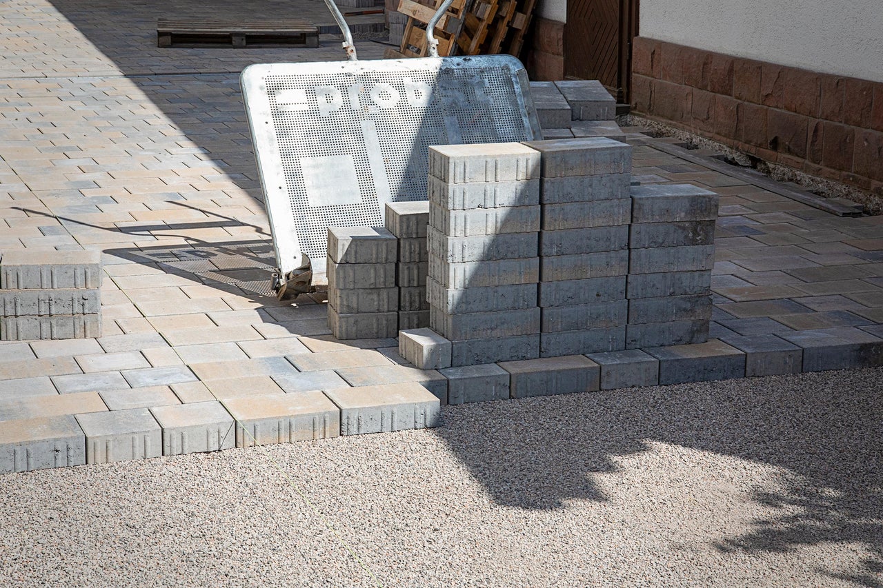 Szene mit Pflastersteinen, Transportwagen und Kies für Gartenbauprojekte