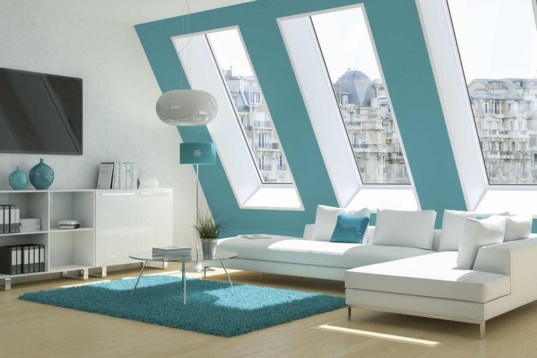 Helles Wohnzimmer mit Dachfenstern, Sofa, Teppich und weißen Möbeln für ein modernes Wohnambiente.