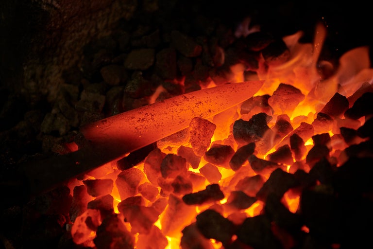 Glühendes Metallstück in Kohle