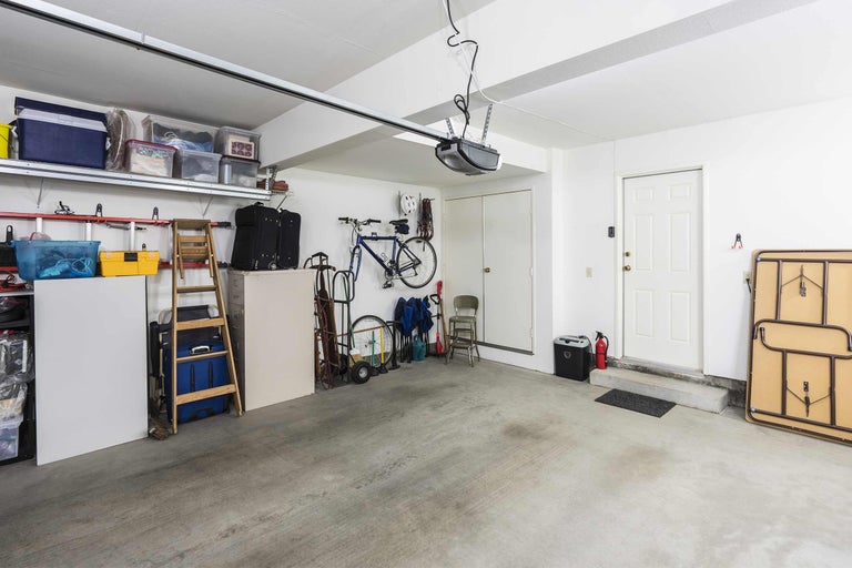 Aufgeräumte Garage mit Regalen, Aufbewahrungsboxen, Fahrrädern und Garagentoröffner
