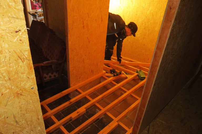 Mann verlegt Holzbalken für einen neuen Boden in einem Raum