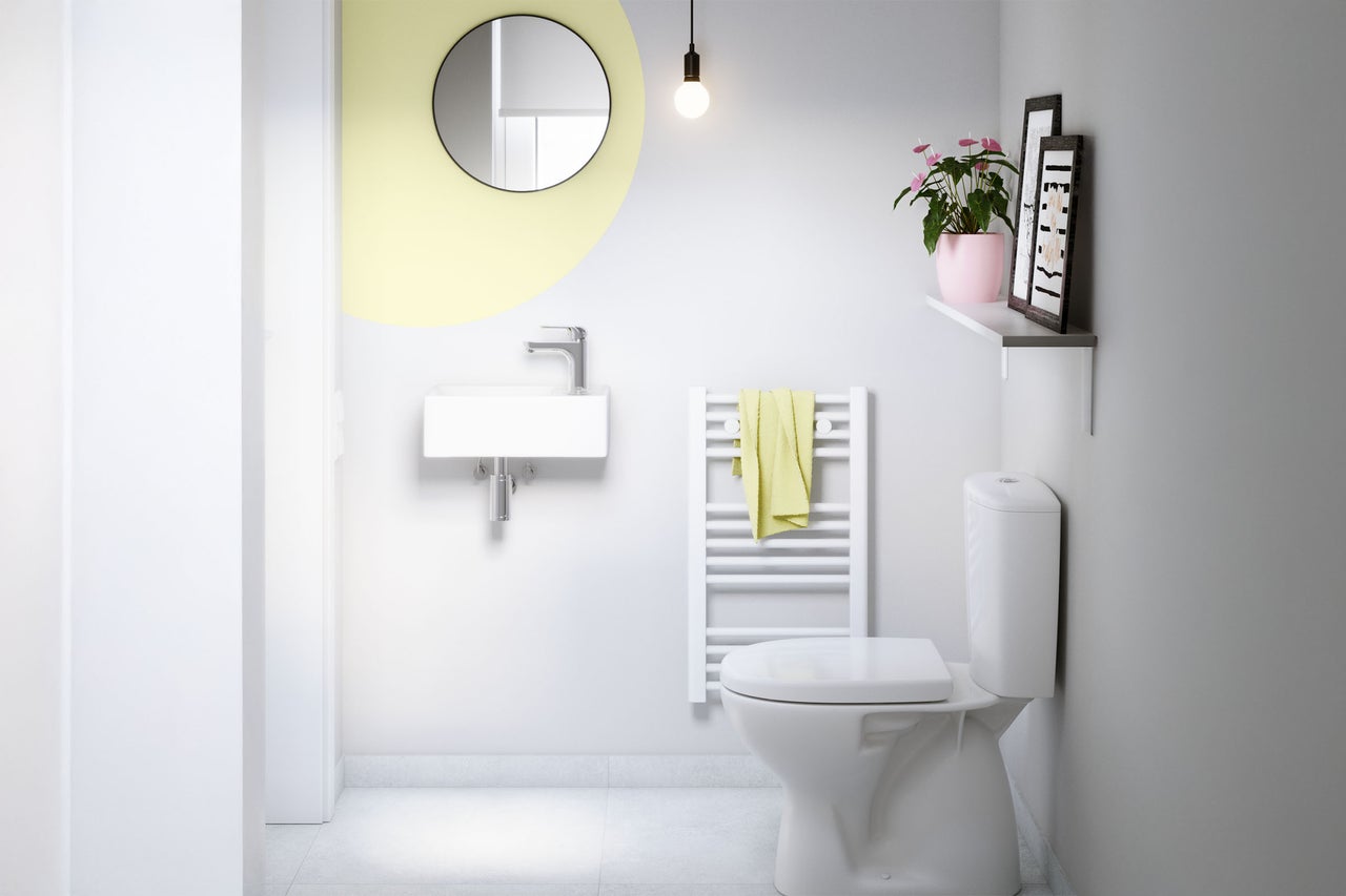 Badezimmer mit Toilette, Waschbecken, Spiegel und Heizkörper