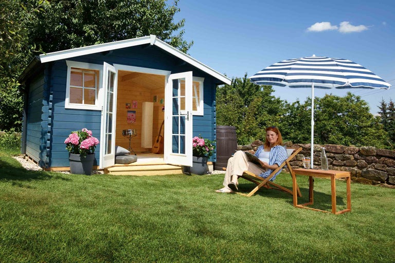 Garten mit Gartenhaus, Sonnenschirm, Liegestuhl und Frau
