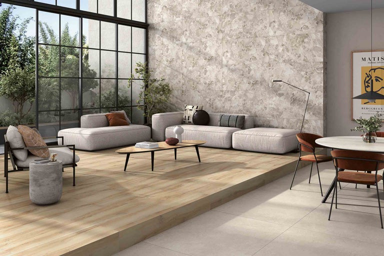 Heller Wohnraum mit Fliesenboden in Holzoptik, Sitzbereich und großer Fensterfront.