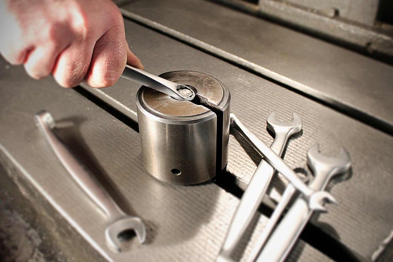 Eine Person verwendet einen Schraubenschlüssel an einer Halterung, um eine Schraube zu befestigen.