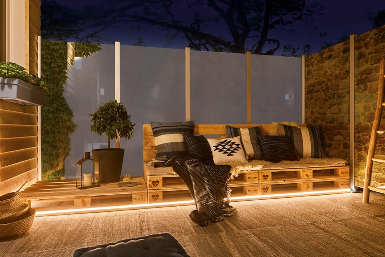 Gestalteter Terrassenbereich mit Holzmöbeln, Pflanzen und dekorativer Beleuchtung