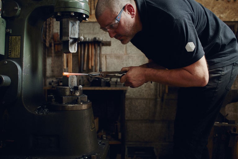 Ein Schmied bearbeitet glühendes Metall mit einer Schmiedemaschine.