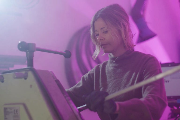 Frau bedient eine Rohrbiegemaschine in einer Werkstatt.