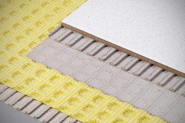 Aufbau einer Bodenfliesenverlegung mit Entkopplungsmatte und Fliesenkleber