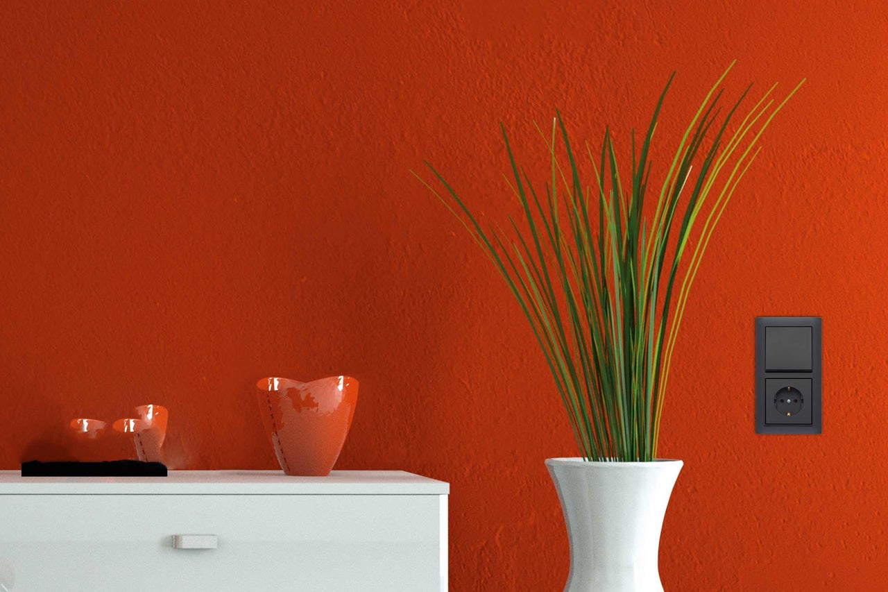 Dekorative Innenszene mit Kommode, Vase, Grünpflanze und Steckdose