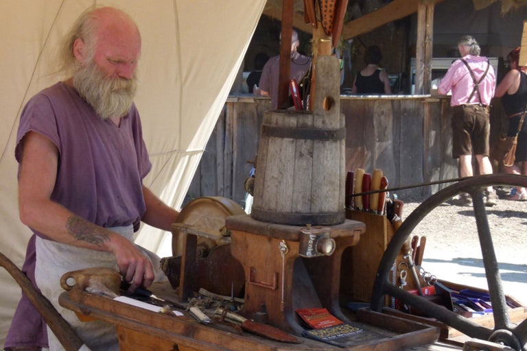 Mann mit Bart schärft Messer an einem Schleifbock