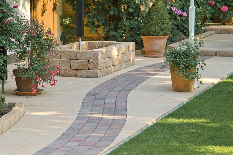 Gartenweg mit Pflastersteinen, Mauer und Topfpflanzen