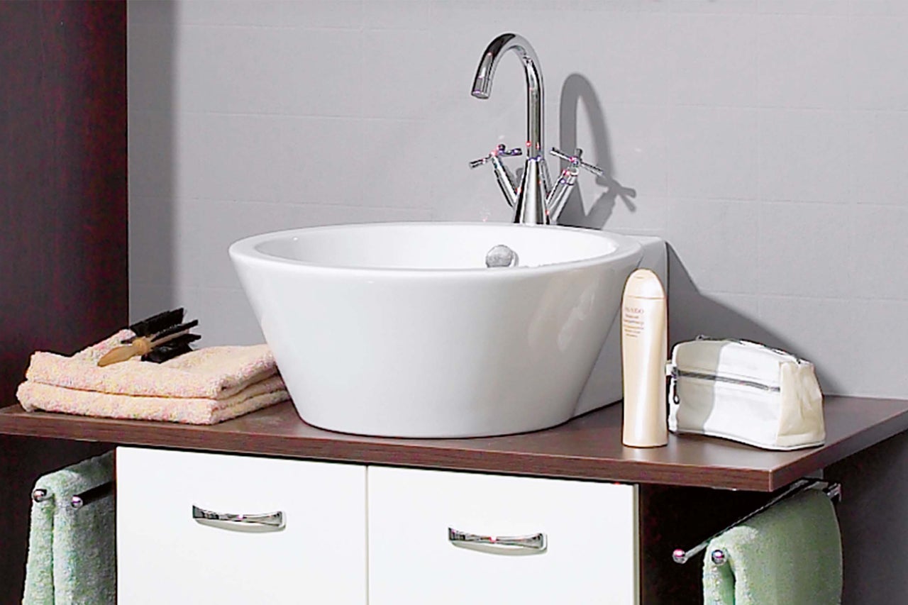Waschbecken im Badezimmer mit Armatur, Handtüchern und Badutensilien