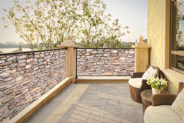 Balkon mit Steinpaneelen als Sichtschutz und Sitzgruppe