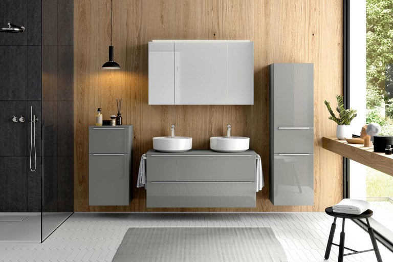 Helles Badezimmer mit Waschtisch, Spiegelschrank und Hochschrank vor Holzwand