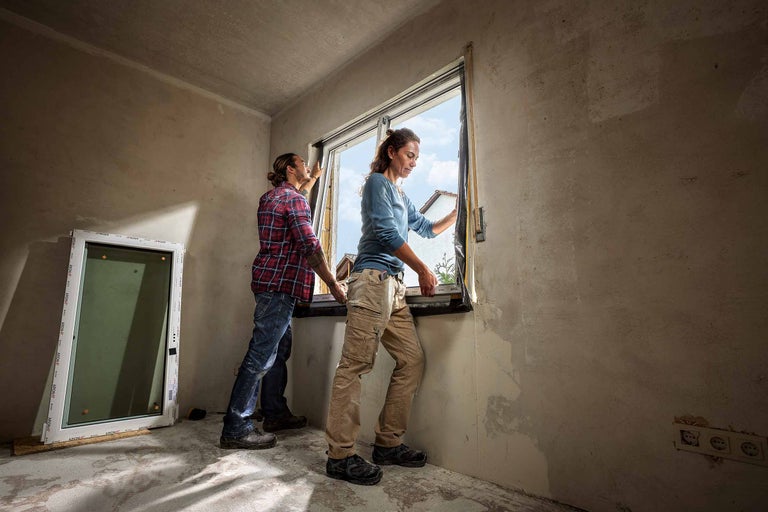Zwei Personen montieren ein Fenster in einem Raum