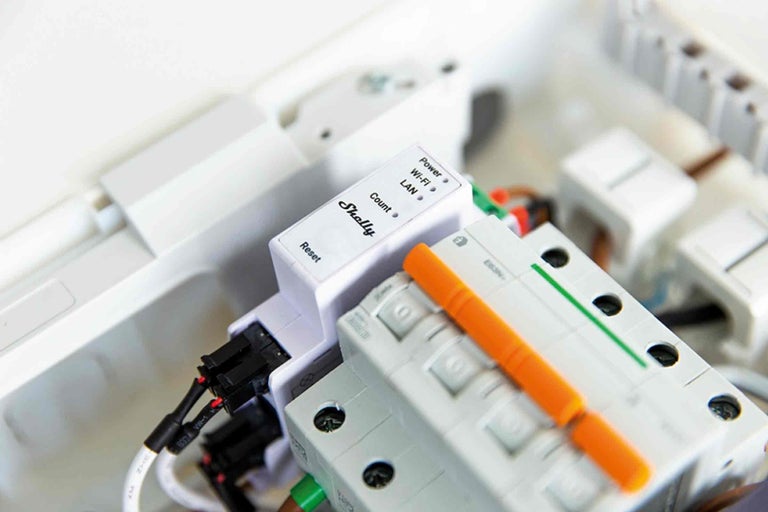 Shelly Logo und ein Energiemessgerät in einem Verteilerkasten