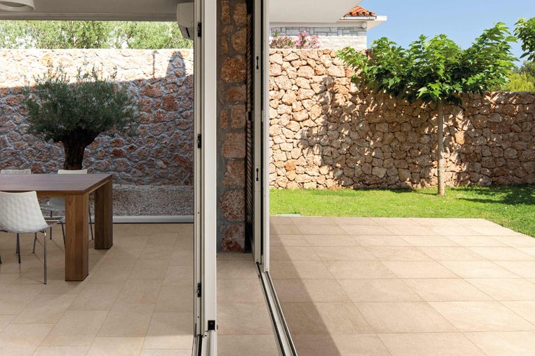 Außenbereich mit Steinmauer, Baum und Bodenfliesen.