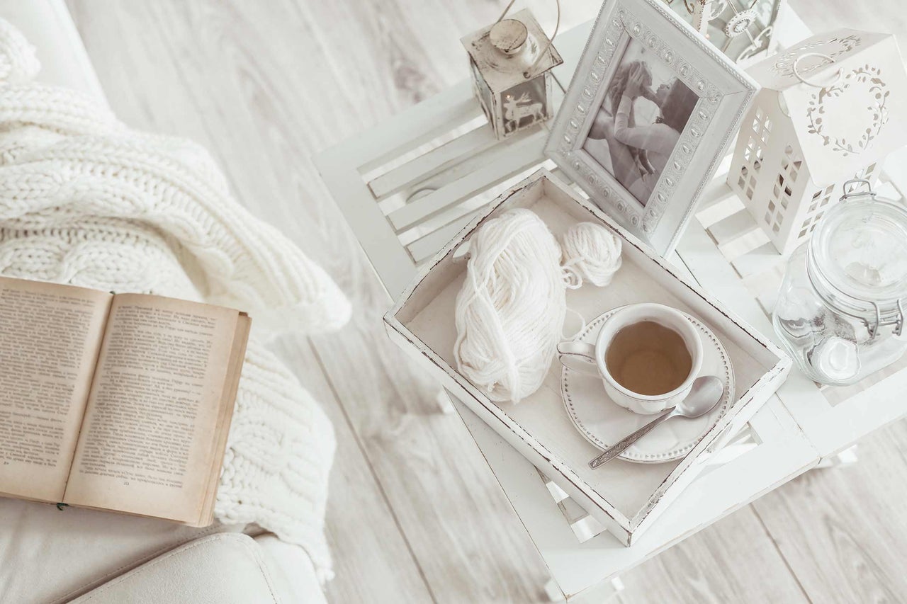 Dekorative Szene mit Buch, Decke, Beistelltisch und Teetasse für eine gemütliche Atmosphäre