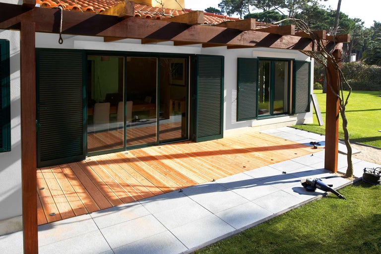 Haus mit Holzterrasse und Steinplatten im Garten