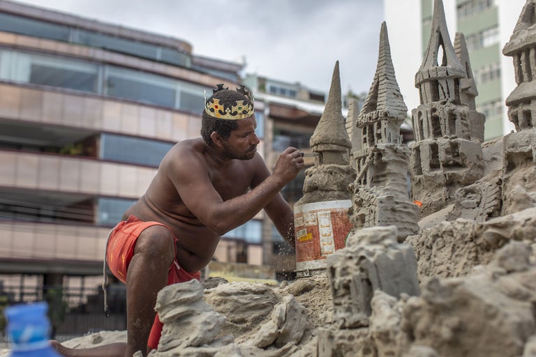 Mann mit Krone formt Sandburg am Strand