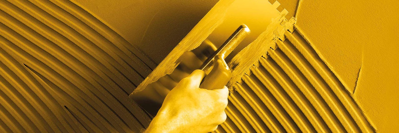 Fliesenkleber wird mit einer Kelle aufgetragen