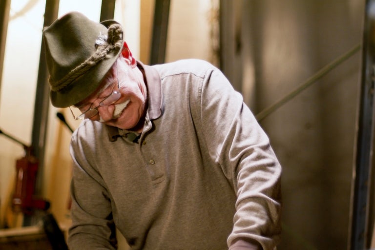 Mann mit Trachtenhut und Poloshirt beugt sich nach unten