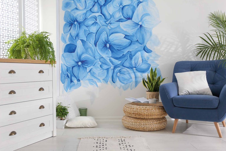 Helles Wohnzimmer mit blauem Sessel, Kommode und Blumenwandbild