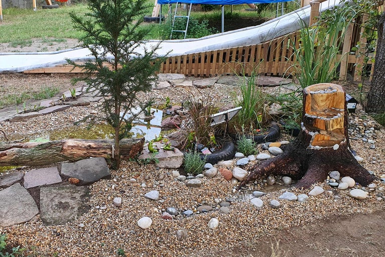 Gestalteter Gartenteich mit Steinen, Baumstumpf und Dekorationen