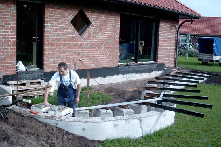 Bauarbeiten an einem Haus mit Fundament, Treppe und einer Person