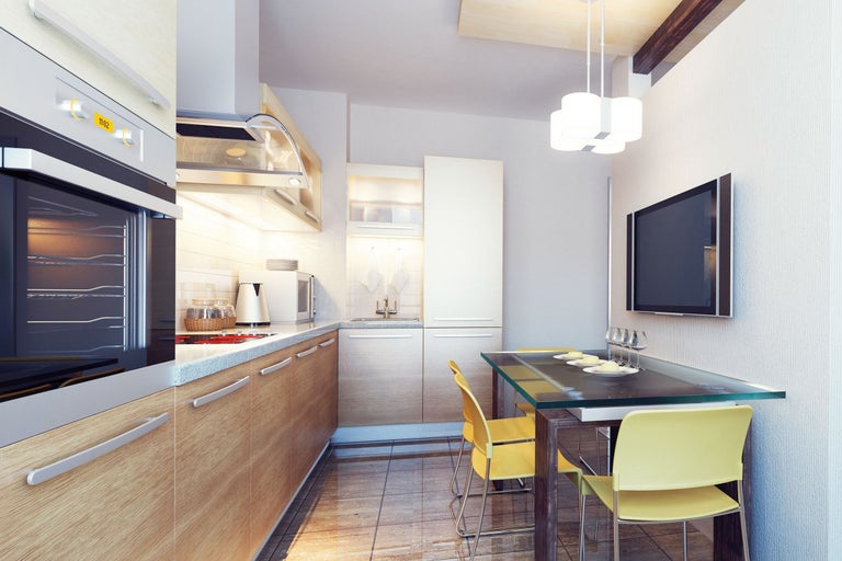 Helle Küche mit Holzfronten, Esstisch aus Glas und Fernseher an der Wand