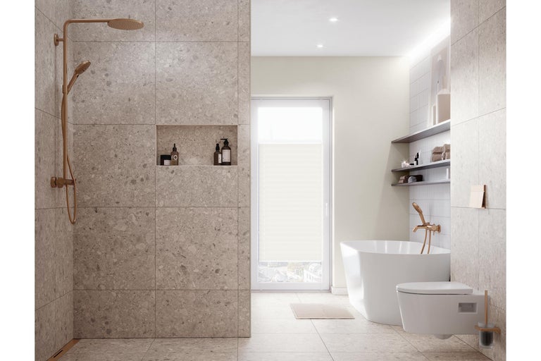Modernes helles Badezimmer mit begehbarer Dusche in Steinoptik, freistehender Badewanne, Wandtoilette und Armaturen in Kupfer-Optik.