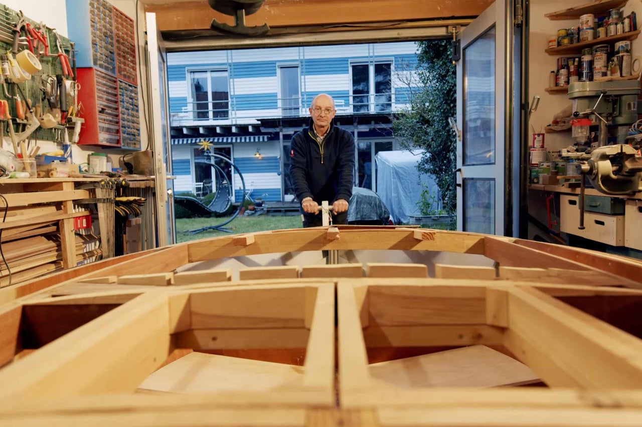 Mann baut Holzboot in Werkstatt.