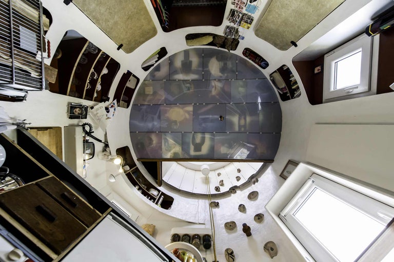 Innenansicht eines runden Zimmers mit Einbauschränken, Fenstern und Klettergriffen an der Wand