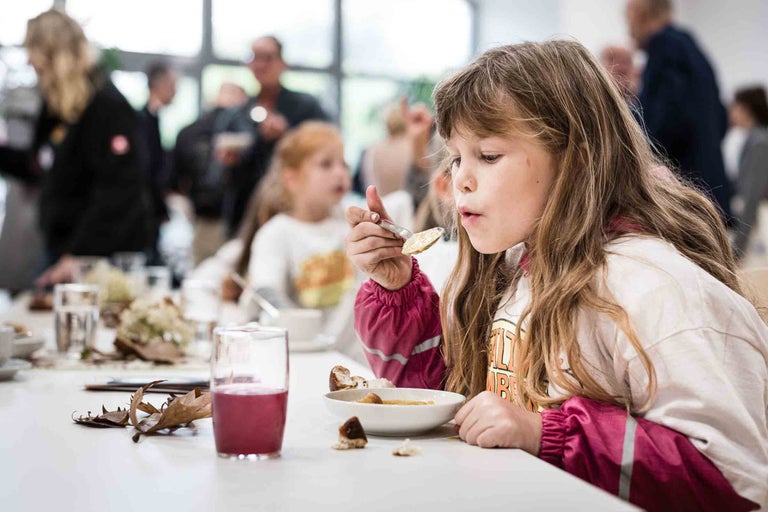 Mädchen isst Suppe am Tisch